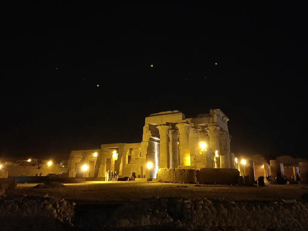 The pillars of the Kom Ombo temple in a scene after sunset with the temple lit up