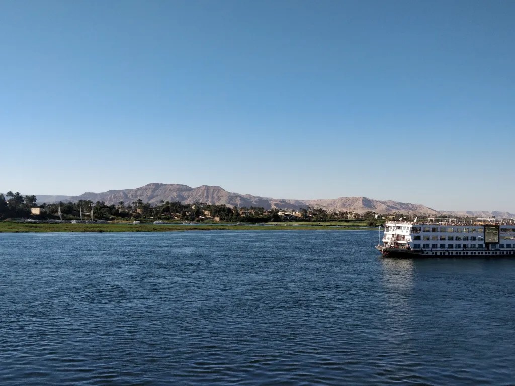 Cruise ship floating away at Luxor Egypt with mountains in the background